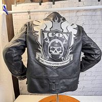 Back view showing large embroidered ICON patch with skull, helmet, and flames with motto.