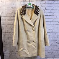 Front view of the cream-colored winter coat with double-breasted buttons and leopard print collar on hanger.