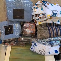 Overview of bedding items including packaged Ralph Lauren blankets, dog pattern comforter, striped blanket, and white throw.