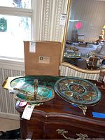Overall view of the Judaica Seder plate, serving tray, and basket on a wooden cabinet with a mirrored background