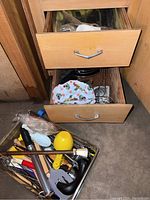 Drawer partially open showing flatware and bowl covers with fruit print