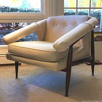 Front left three-quarter view showing overall design, upholstery, armrests, wood frame and legs