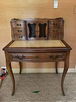 Front view of vintage Meldan Furniture writing desk showing wood finish, curved legs, five drawers and two cabinet doors with lattice pattern.