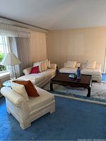 Sectional sofa with chaise and two chairs around a wooden coffee table with pillows on sofas.