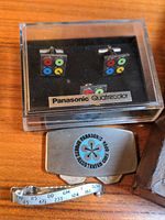 Photo of Panasonic Quatracolor cufflinks in case and money clip with golf pro logo and golf score bar on wooden surface