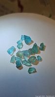 Cluster of approximately 15 rough natural apatite crystals in lagoon blue shades placed on white background.