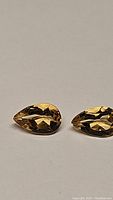 Close-up view of two pear-shaped natural golden citrine gemstones showing faceting, color, and clarity