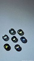 Seven round cabochon sapphires in various colors including blue, green, and yellow, laid out on a surface for clear identification.