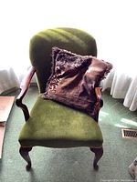 Front view of green upholstered arm chair with a purple decorative pillow on the seat.