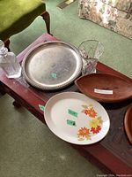 Silver plated serving tray, two wooden bowls and ceramic floral platter on wood coffee table