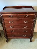 Front view of solid wood dresser showing six drawers and ornate carved corners with claw feet.