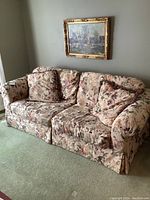 Front angled view of the floral sofa showing overall shape, fabric pattern, and cushion arrangement.