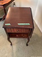 Solid wood end table with drop leaf side extended, drawer with knob, and lower shelf visible. Shows overall condition.