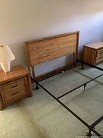 Full set view: queen headboard mounted on metal frame with two matching nightstands on carpeted floor