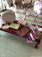 Wide view of all items on a wooden table including the round case, muff, boxes, and scarf