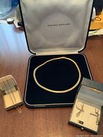 Three gold chain necklaces and one pair of drop earrings in boxes on table