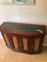 Front view of wood hall cabinet with carved door panels and stone top showing overall condition.