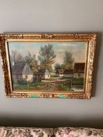 Front view of the framed oil painting showing village houses, trees, path, and water canal.