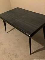 Photo showing the dark wood rectangular table from an angle, highlighting the curved legs and wood grain texture on the tabletop.