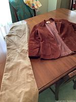Brown corduroy Levi's jacket and beige pants laid on a wooden table, showing full garments and fabric texture