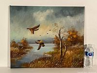 Full view of oil painting showing ducks in flight over wetlands with grasses, tree, water, and cloudy sky.