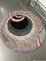 Overhead view of the full round rug showing concentric circle pattern with black center and multicolored rings