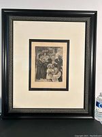 Full view of framed 'La Famille' heliogravure showing black decorative frame and double matting around the print.