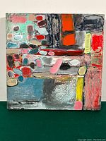 Front view of square canvas painting with abstract colored blocks and ovals