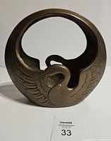 Front view of brass basket showing swan/phoenix design with handle formed by neck and circular shape.