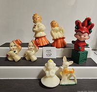 Full view of seven Gurley Christmas candles arranged on steps including choir singers, two dancing snowmen, angel, reindeer, and elf on jack-in-the-box.