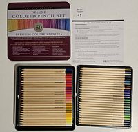 Open metal tin displaying two trays holding 50 colored pencils arranged by color, showing the natural wooden barrel with color tips and Studio Series branding on each pencil.