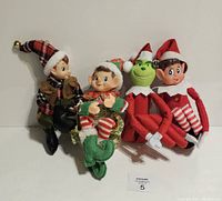 Four modern Christmas knee hugger dolls sitting side by side against a white background, showing full bodies and festive clothing.