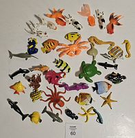 Top-down image showing 30 small colorful sea life plastic toy figures arranged on a white surface.