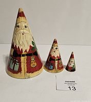 Full view of all three Santa nesting dolls arranged in size order showing conical shape and hand painted details.