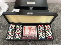 Open view of one poker chip set showing poker chips, deck of cards, and dice inside wood case.