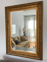 Front view of mirror hung on wall, reflecting living room.