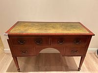 Front view of antique ladies writing desk showing green leather top and five drawers with decorative handles and inlay.
