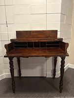 Front view of antique spinet desk with fold-over top open showing small storage cubbies above the writing surface.