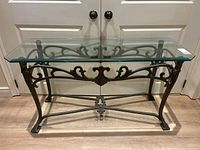 Front angle view of the console table showing cast iron base and clear beveled glass top.