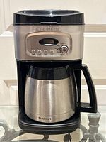 Front view of Cuisinart coffee maker showing chrome finish, control panel with buttons and dial, and stainless steel thermal carafe with black handle and lid.