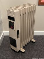 Side view of the beige electric space heater showing seven fins and built-in cord compartment.