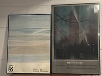 Photo of both framed posters side by side showing the Expo 86 poster on the left with abstract horizontal bands of color and the Metropolitan Museum photography poster on the right featuring a nighttime silhouette of the Washington Monument