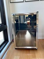 Front view of stainless steel bar fridge with glass door and chrome handle