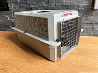 Angled side view of the Petmate Pet Taxi dog crate showing ventilation holes and metal door with latch.