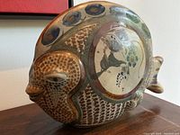 Side profile view of the pottery fish sculpture showing the side eye glance face and painted round floral decoration on the body