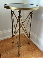 Full view of round marble top side table with brass-finished tripod base
