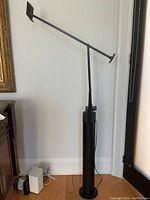 Full view of lamp upright showing cylindrical base, vertical support and adjustable arm.