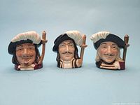 Front view of 3 Musketeers Toby mugs showing detailed facial features, hats with feathers, and sword hilts