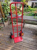 Red steel dolly standing upright, showing frame and tires.
