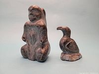 Front view of Inuit soapstone female figure and raven sculptures with dark polished finish.